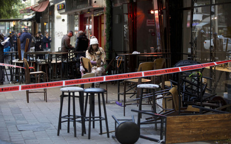 An Israeli eye witness sits with her dog at the scene of a shooting attack in Tel Aviv, Israel, Friday, Jan. 1, 2016. A gunman opened fire at a popular bar in the central Israeli city of Tel Aviv on Friday afternoon, killing two and wounding at least three others before fleeing the scene, police said. (AP Photo/Oded Balilty)