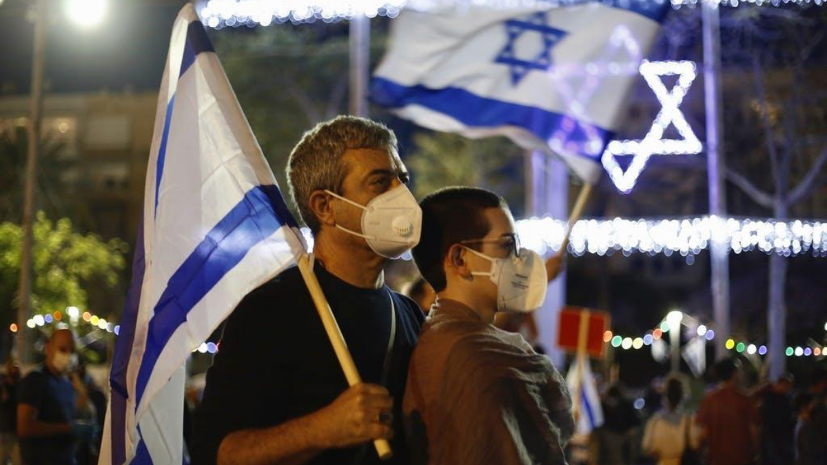 israeliani con la bandiera di Israele e le mascherine