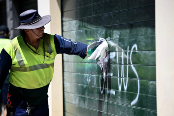 Un poliziotto in Australia rimuove la scritta Jews dalla serranda di un negozio