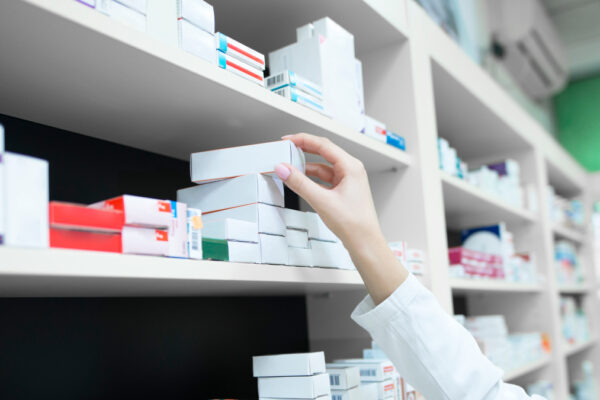 mano di donna prende farmacie su scaffali di farmacia