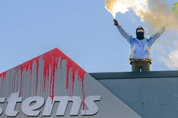 Un manifestante di Paletsine Action imbratta l'insegna di Elbit Systems