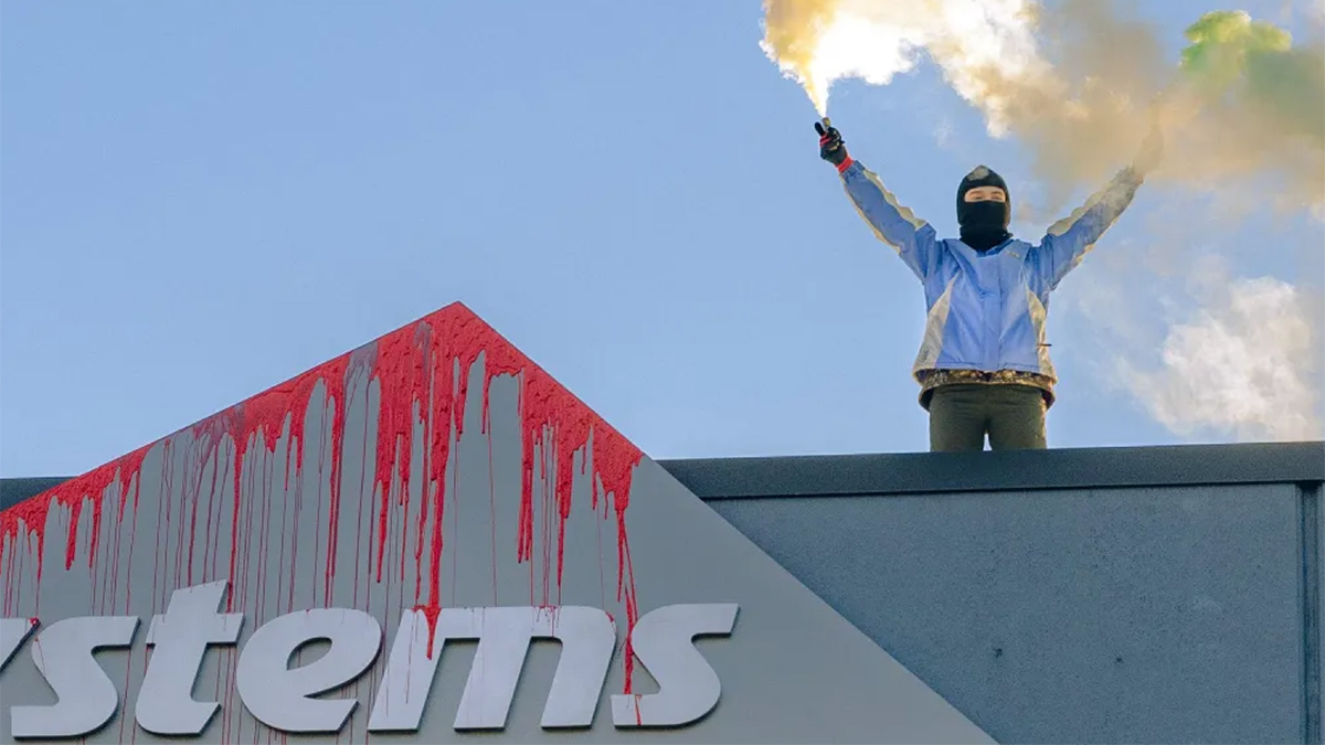 Un manifestante di Paletsine Action imbratta l'insegna di Elbit Systems
